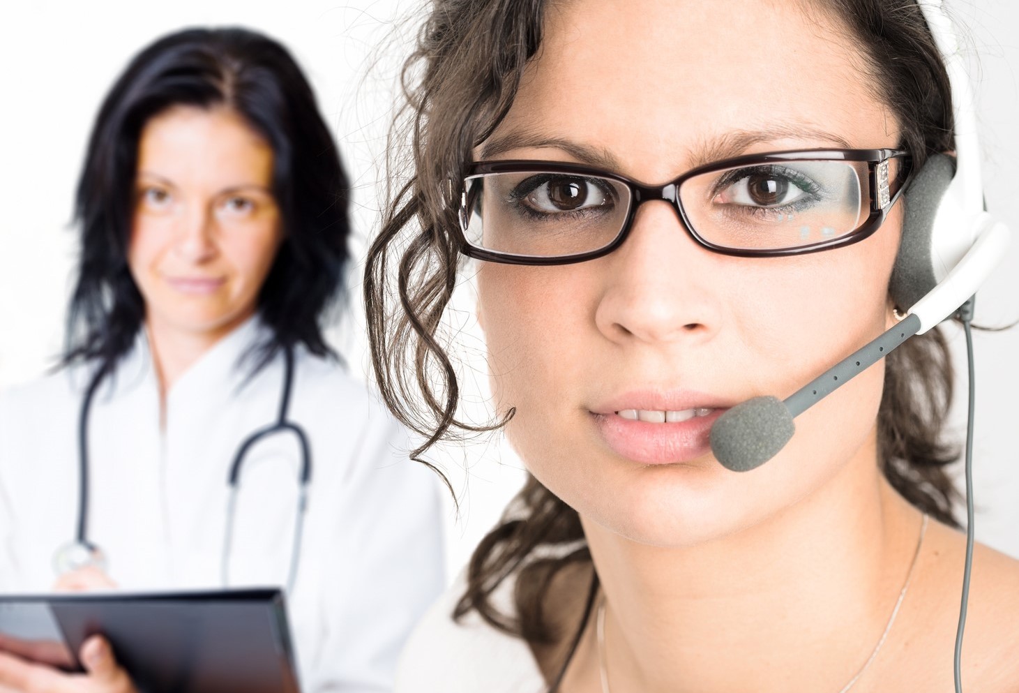 Triage Answering Service Operator wearing glasses and a headset stands in front of a triage nurse holding a clipboard and wearing a stethoscope.