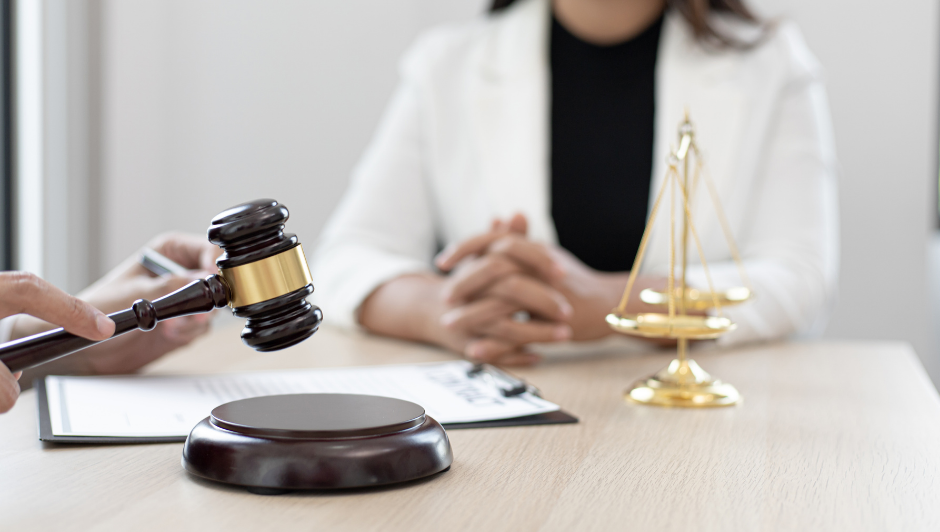 Medical liability concept: A nurse sits at a table with a clipboard, gavel, and golden scales of justice.