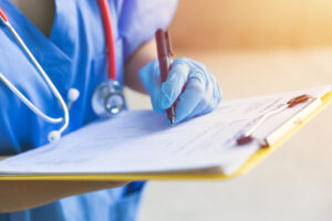 A telehealth triage nurse fills out a checklist on a clipboard for patient care quality.