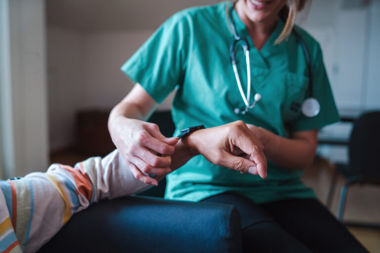 A nurse attaches an RPM device to a patient's wrist.