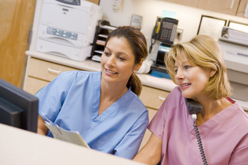 Two nurses at a clinic use nurse triage software to document a patient caller's symptoms.