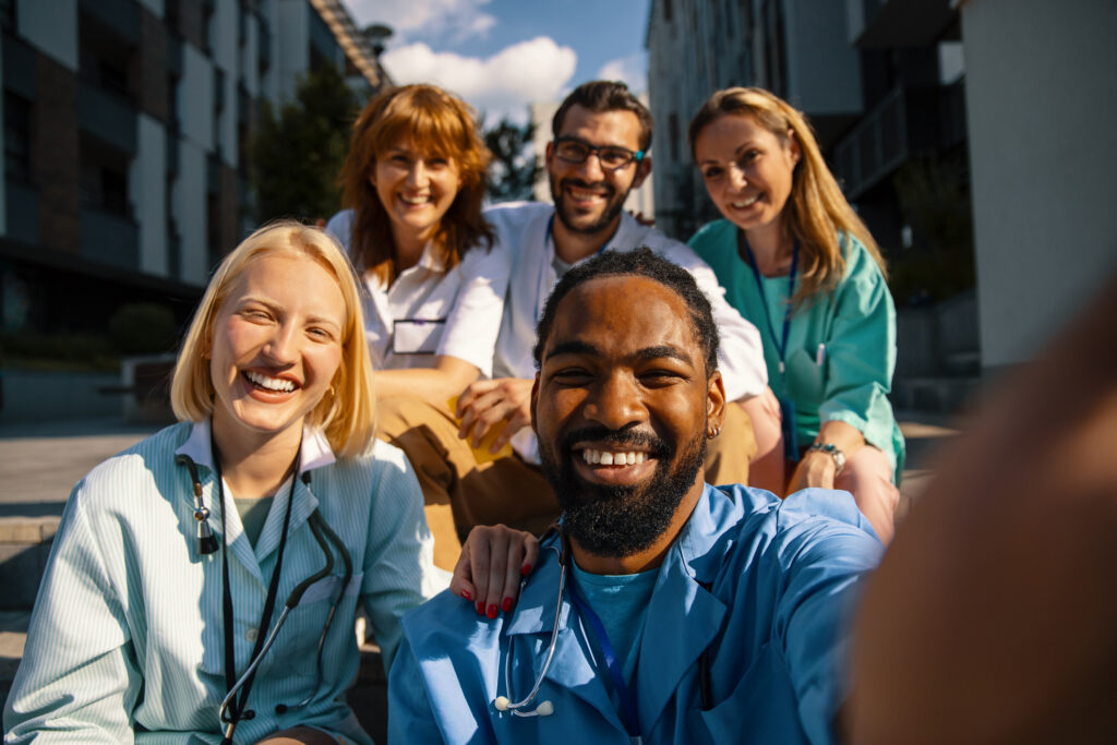 A group of nurses from a nurse triage business take a photo together outside.