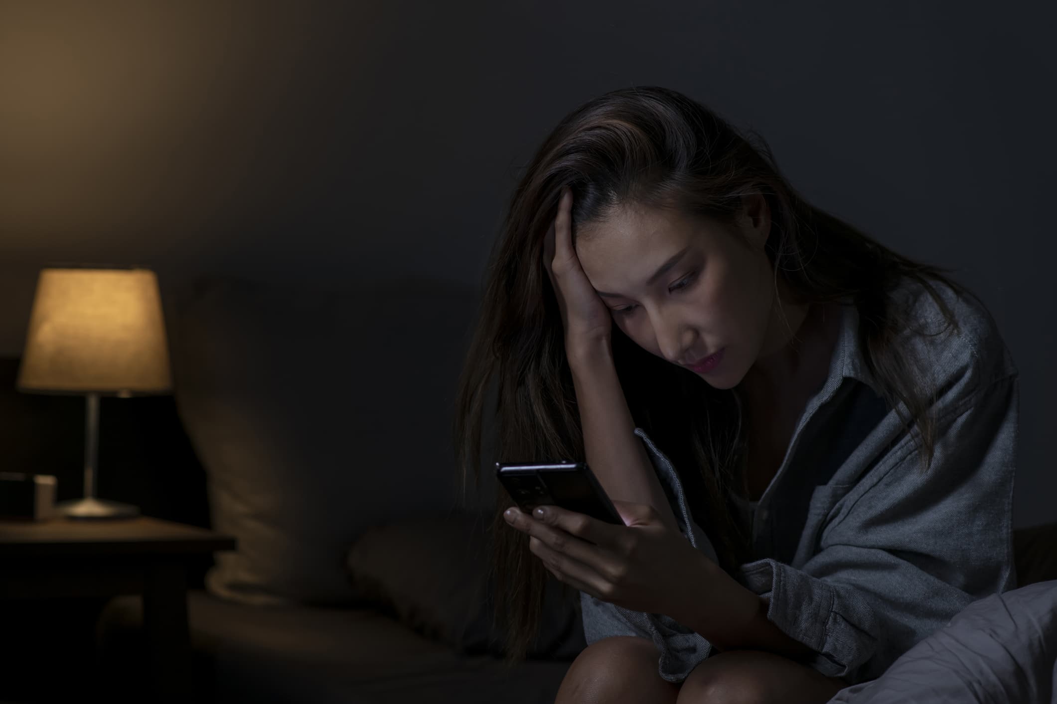 A woman sitting in bed at night phones her doctor's office while experiencing a sudden-onset headache, one of several symptoms that patients call about after normal office hours.