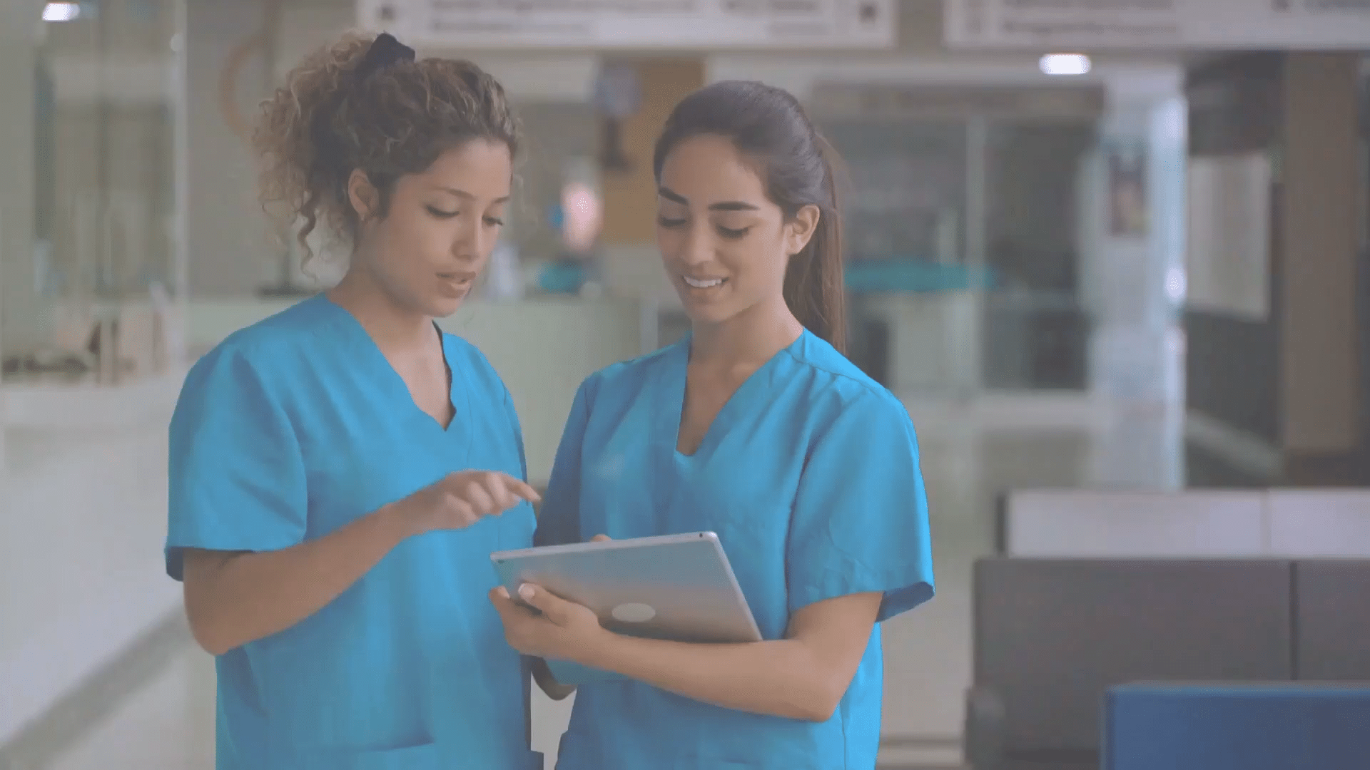 Two triage nurses review patient data on a tablet.