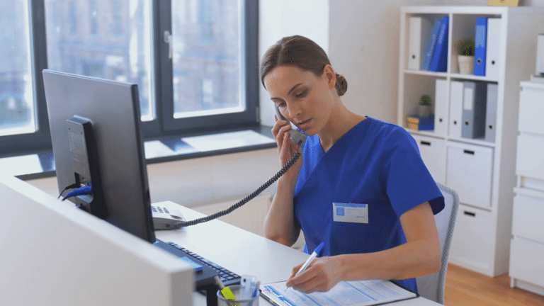A nurse writes notes on a clipboard while talking with a patient over the phone about their health symptoms and triage disposition. Nurse talking to patient. Nurse using protocols. Nurse assessing patient needs. Nurse assessing urgency using protocols.