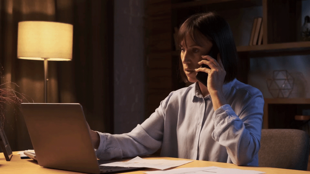 A patient sitting at their desk at home talks with a triage nurse over the phone.