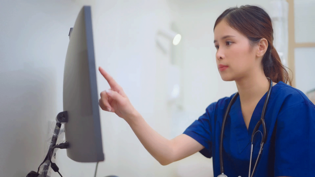 A member of a healthcare team reviews notes from MedMessage Assist on her computer monitor.