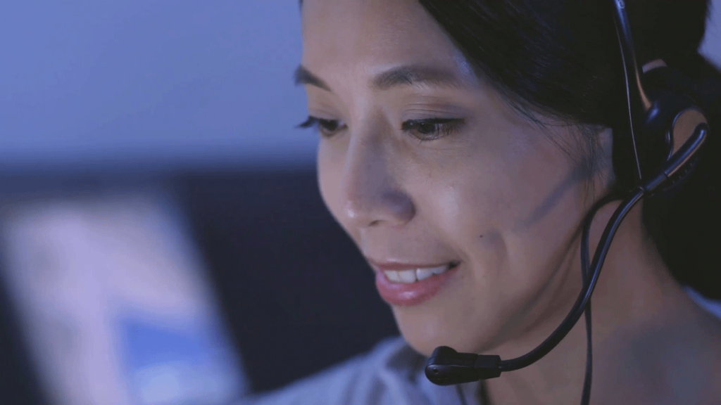 A triage nurse talks with a patient over her headset.