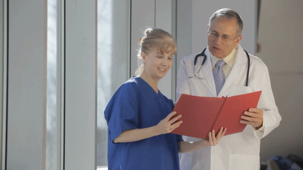 A nurse reviews a folder of information with a doctor.