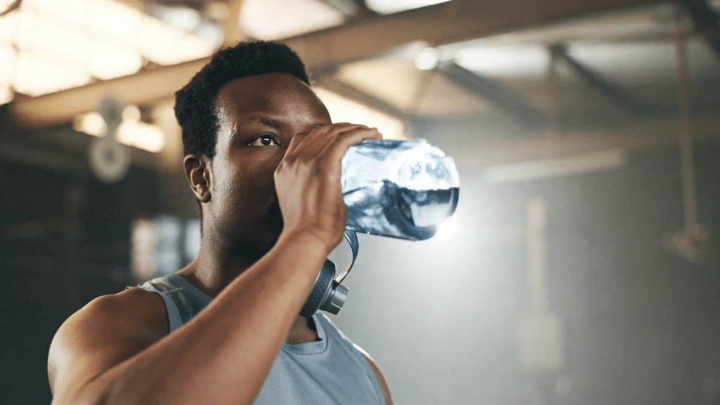 An athlete drinks water while practicing in a gym.