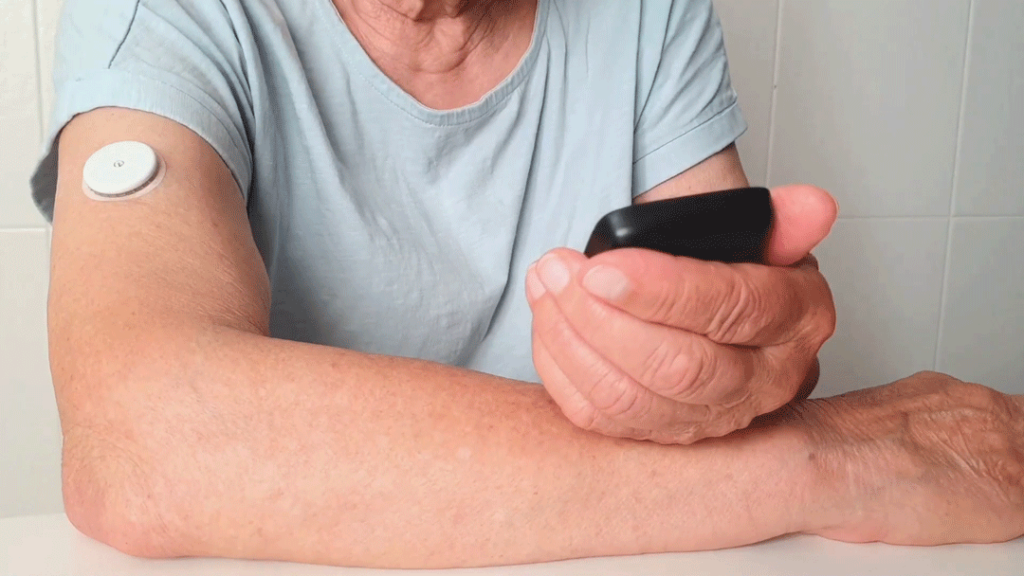 Chronic disease management example: a patient checks their blood sugar levels using an RPM sensor on their arm.