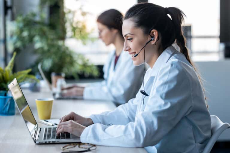 Nurse triage services concept: two nurses work on laptops to document patient calls.