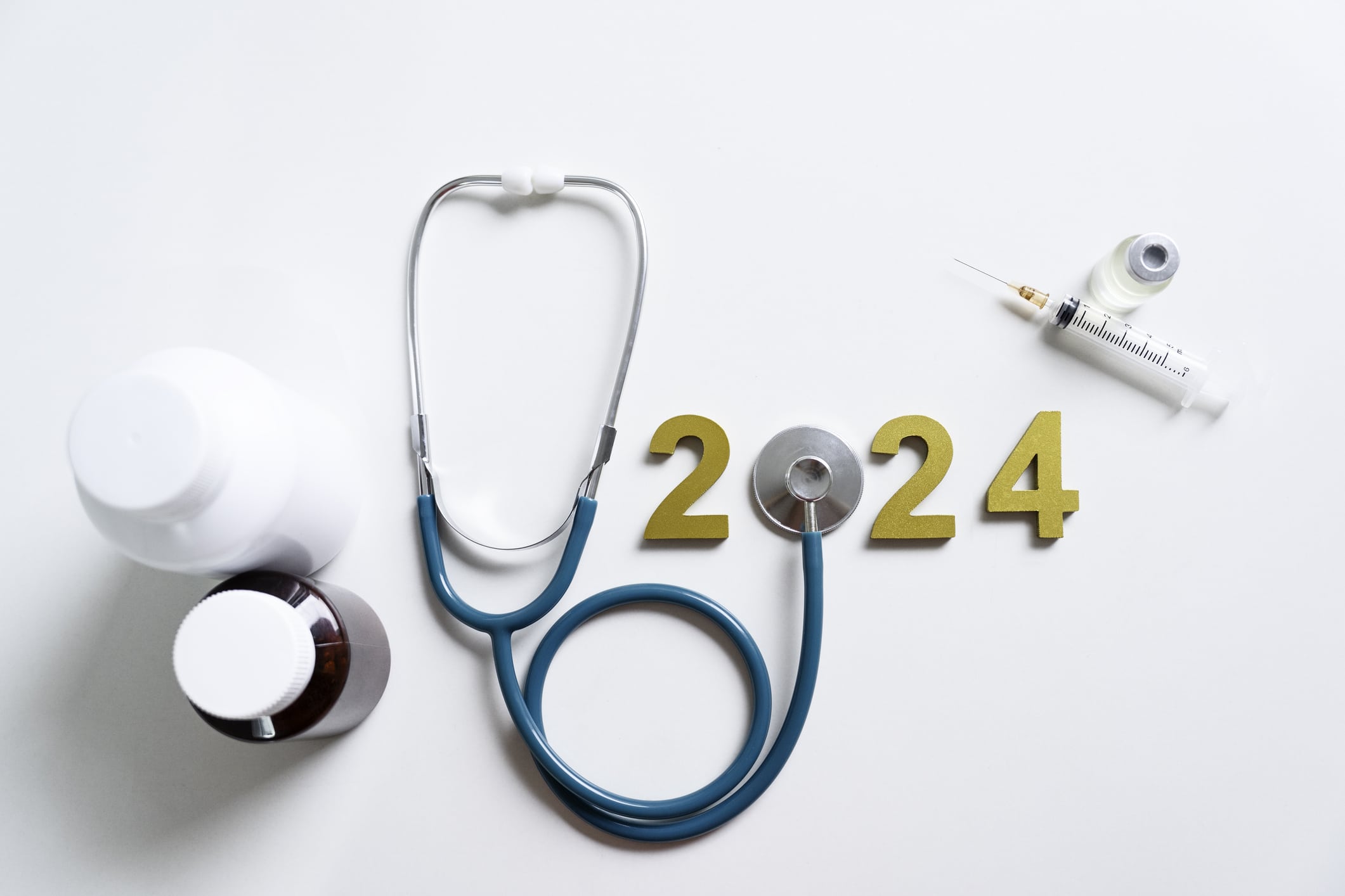 Advancing telehealth triage concept. A stethoscope's diaphragm is used to form the first 0 in 2024. Other medical items are arranged around it, including bottles and a syringe.