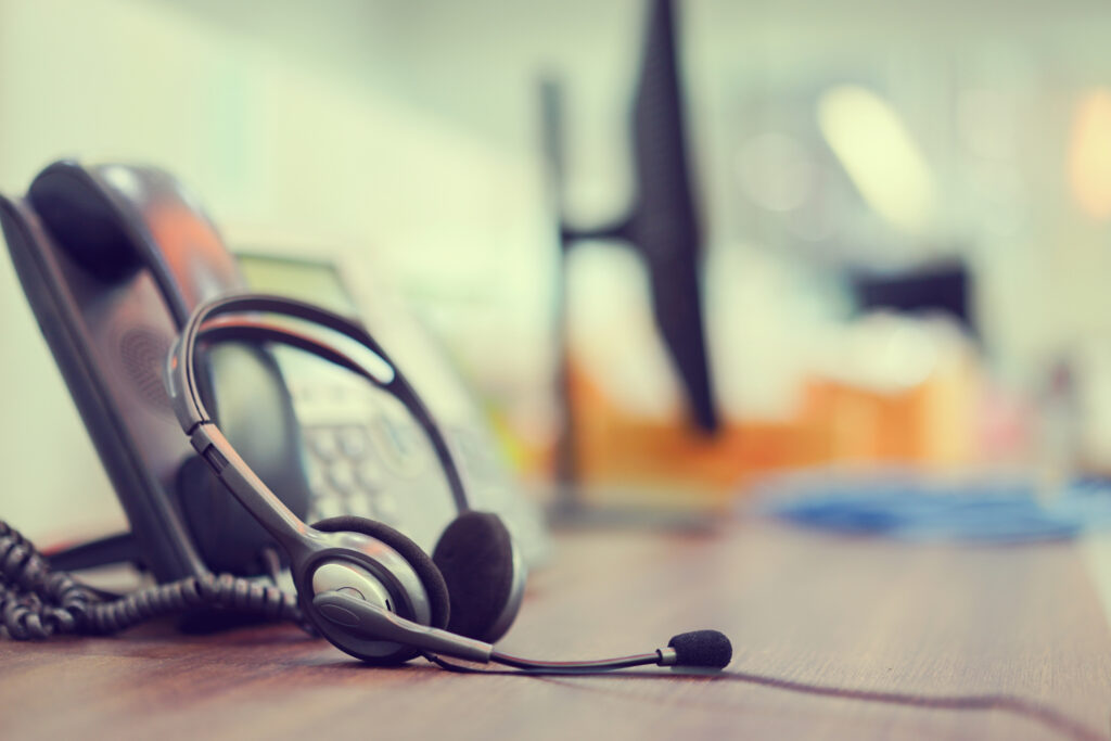 A medical headset is set against a phone at a nonclinical operator's workstation.