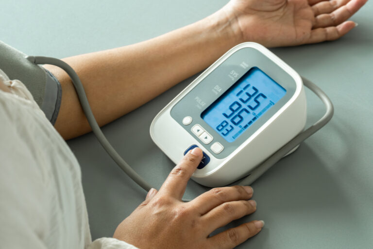 A woman uses a digital blood pressure monitor.