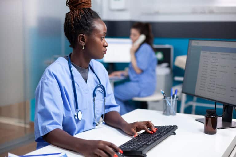 A nurse sits at a computer station using triage software.