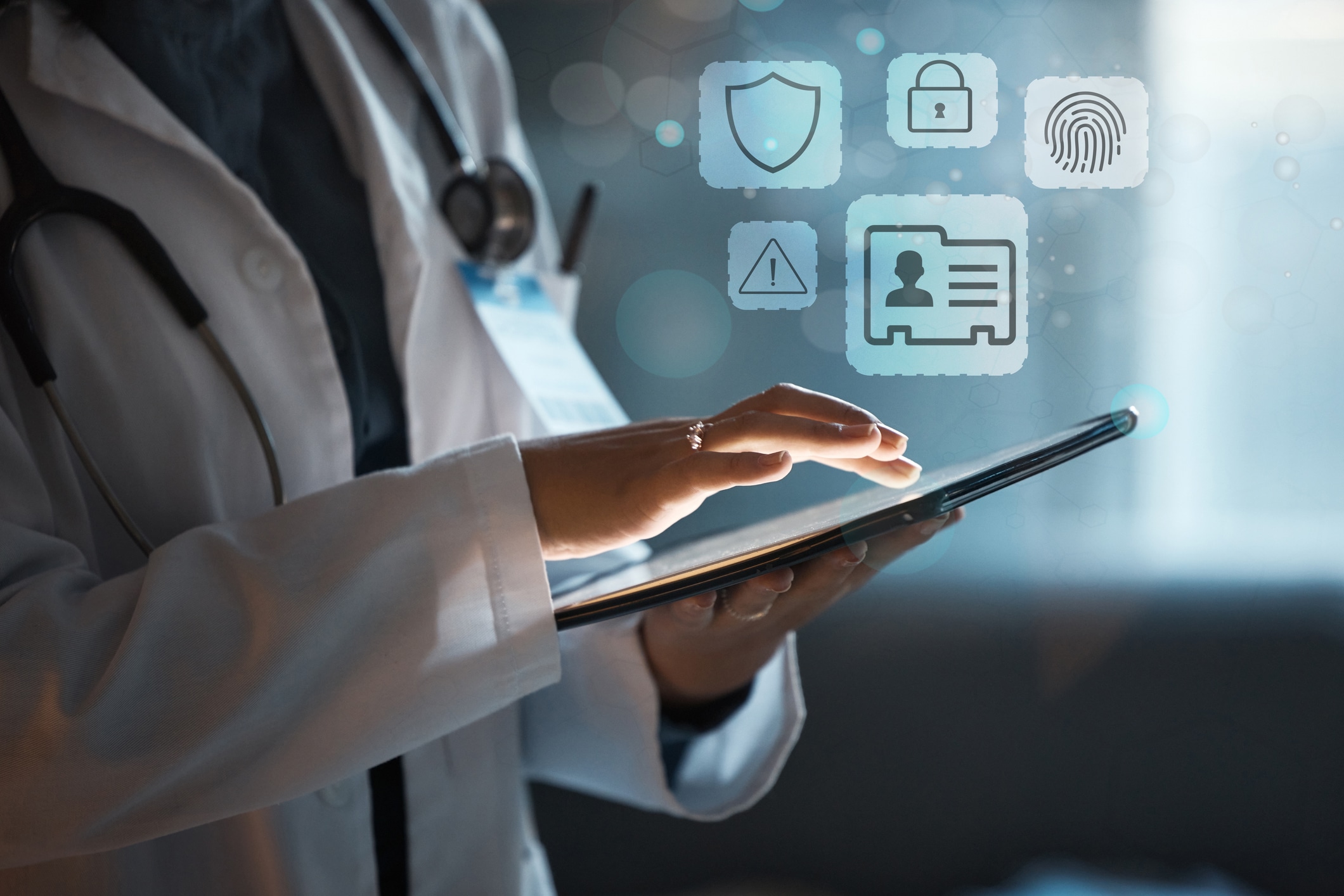 A clinician uses a tablet to check medical intake and secure messages. Icons representing a patient file hover above the tablet.