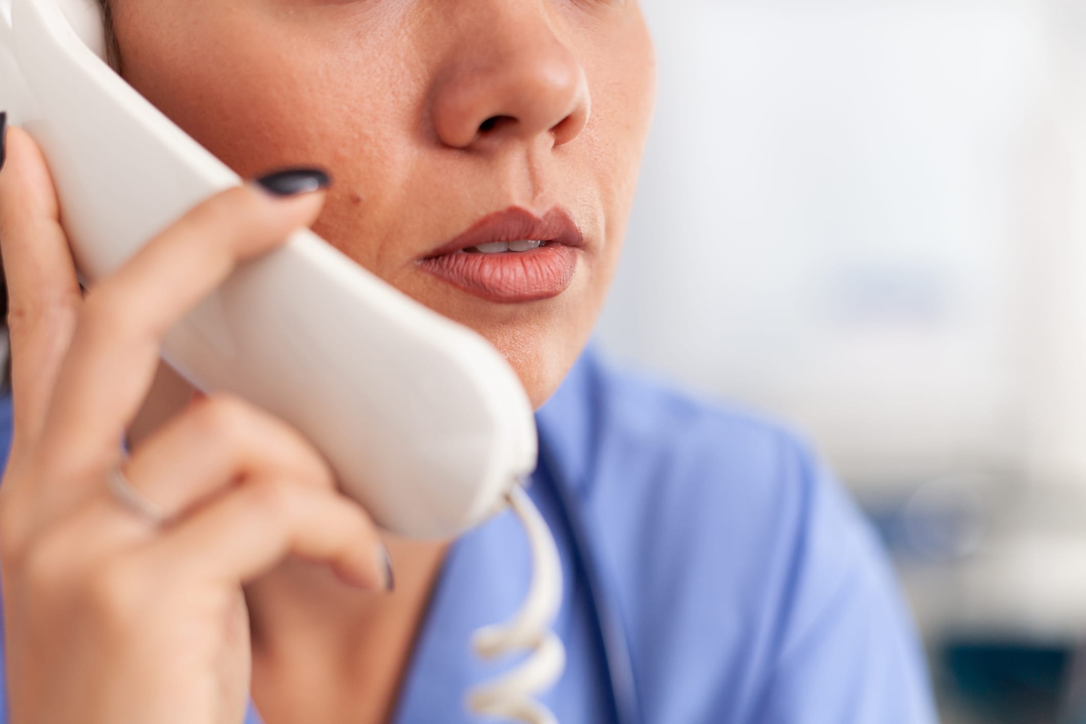 Headshot of a nurse answering a patient call using a landline phone.