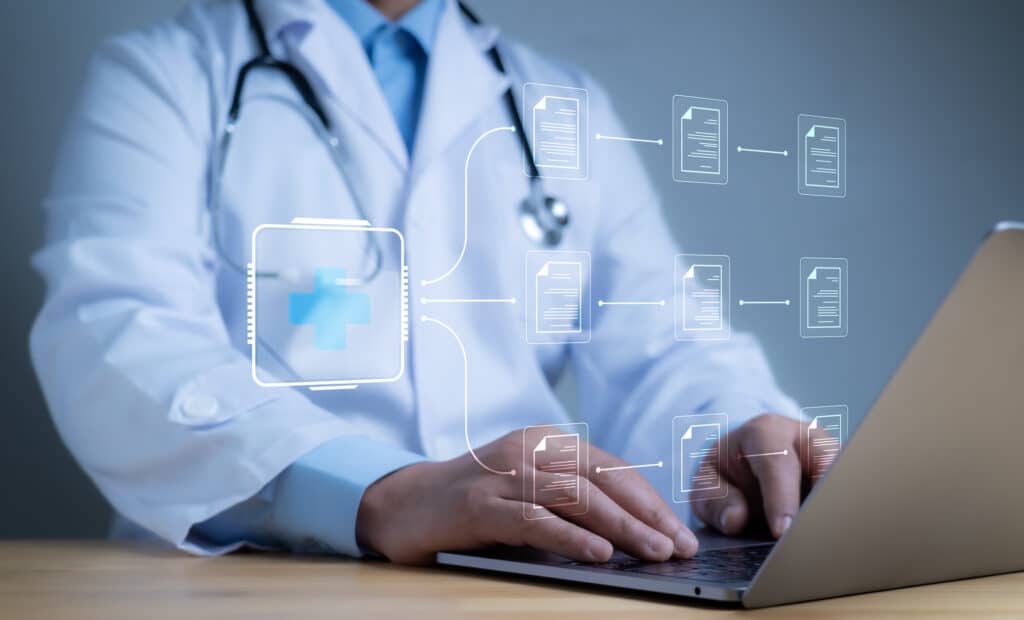 A medical record filing system is superimposed over a doctor working on their laptop.