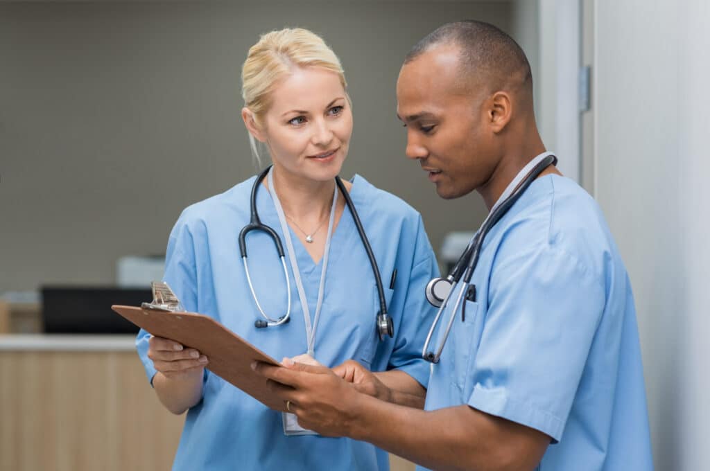 Two nurses review patient information on a clipboard.