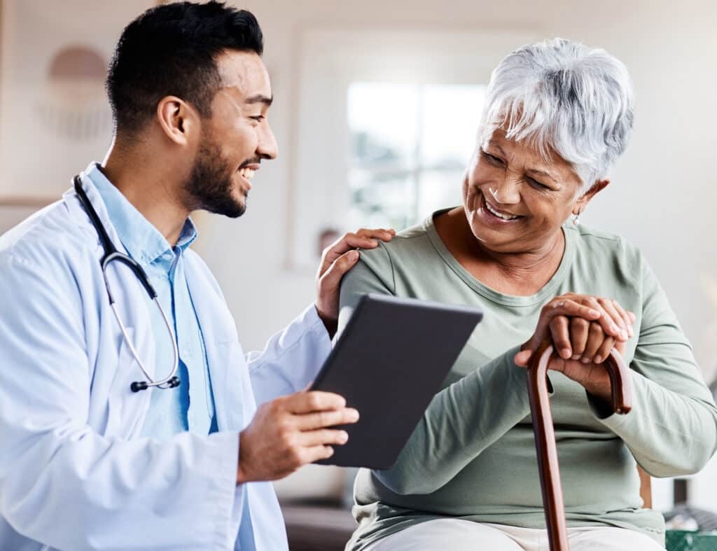 A doctor supports wellness and shares positive test results on his tablet with a geriatric patient.