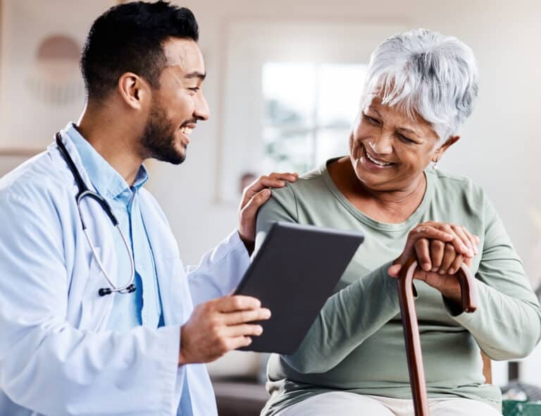 A doctor supports wellness and shares positive test results on his tablet with a geriatric patient.