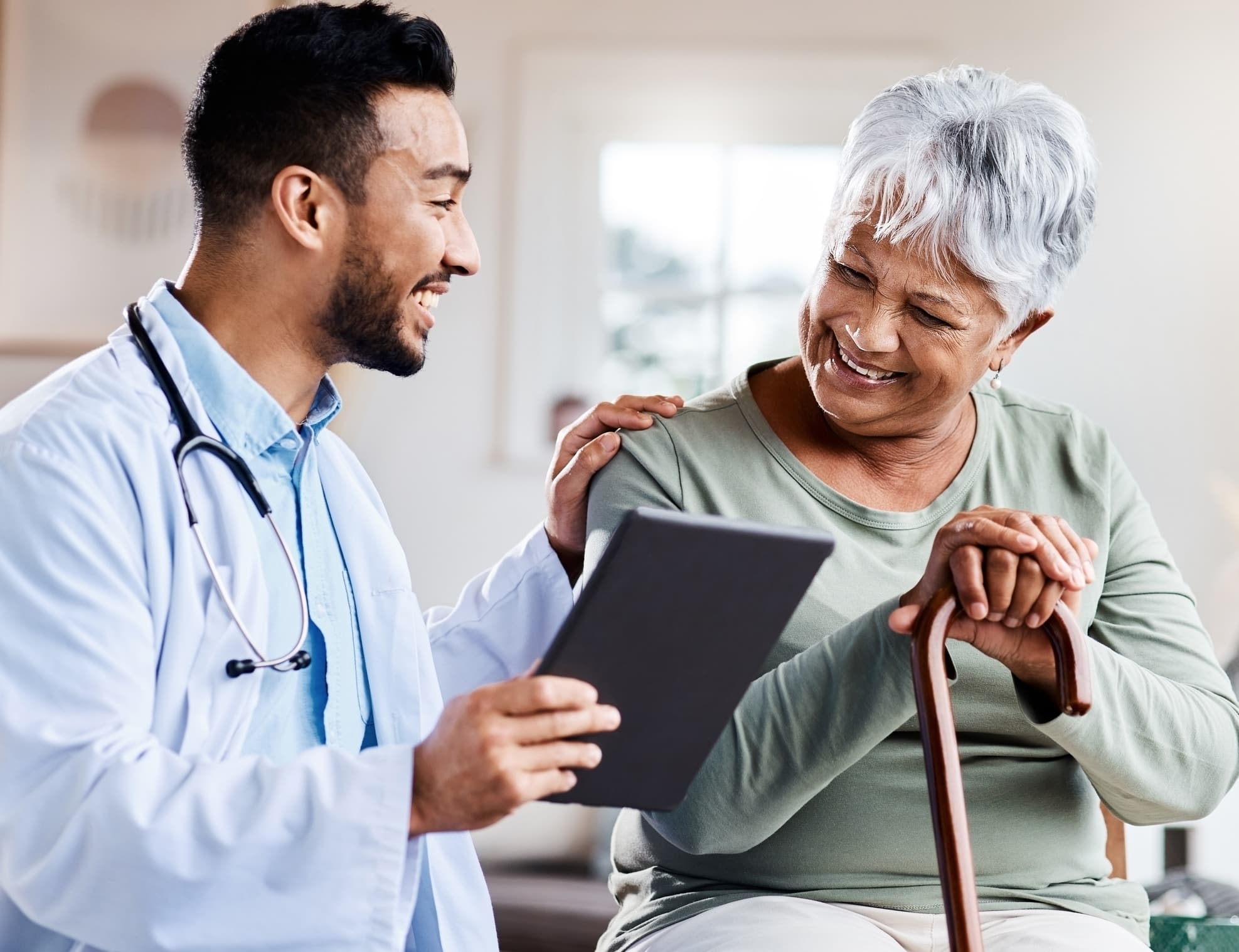 A doctor supports wellness and shares positive test results on his tablet with a geriatric patient.