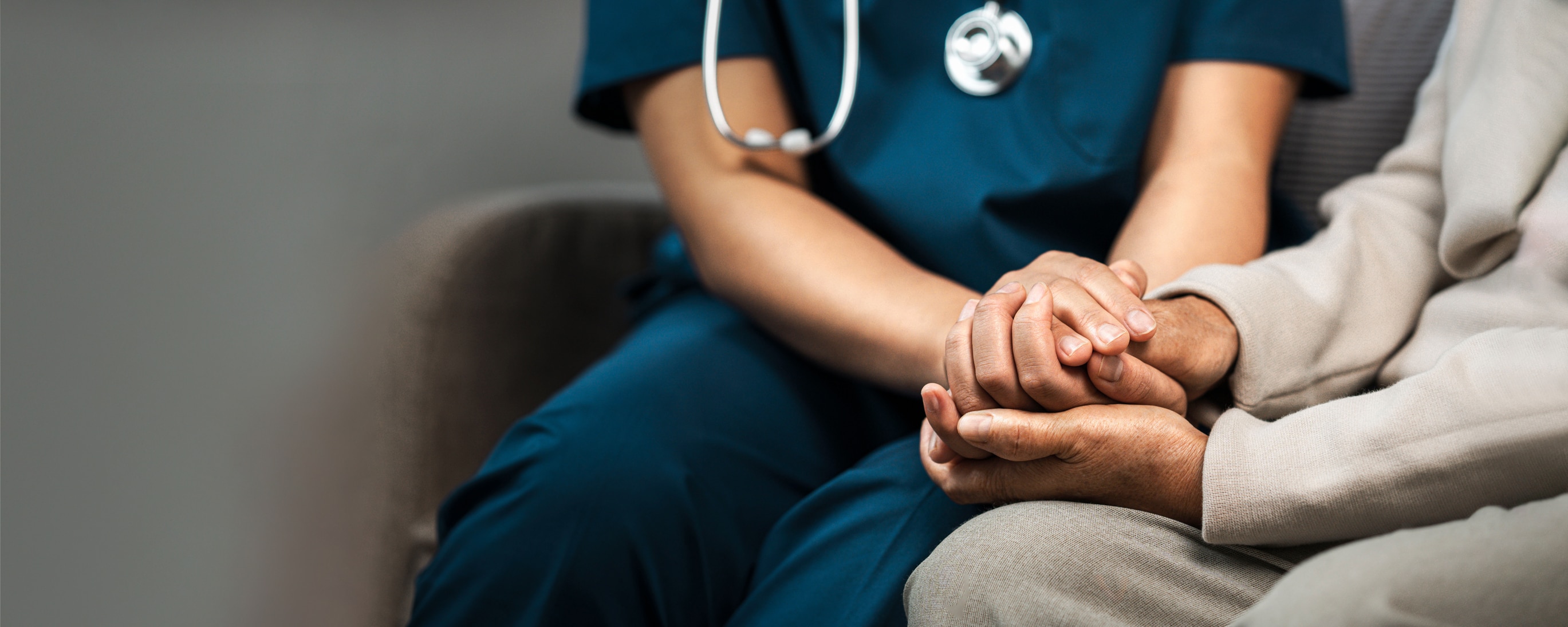 A triage nurse holds hands with a patient, representing improved patient outcomes.