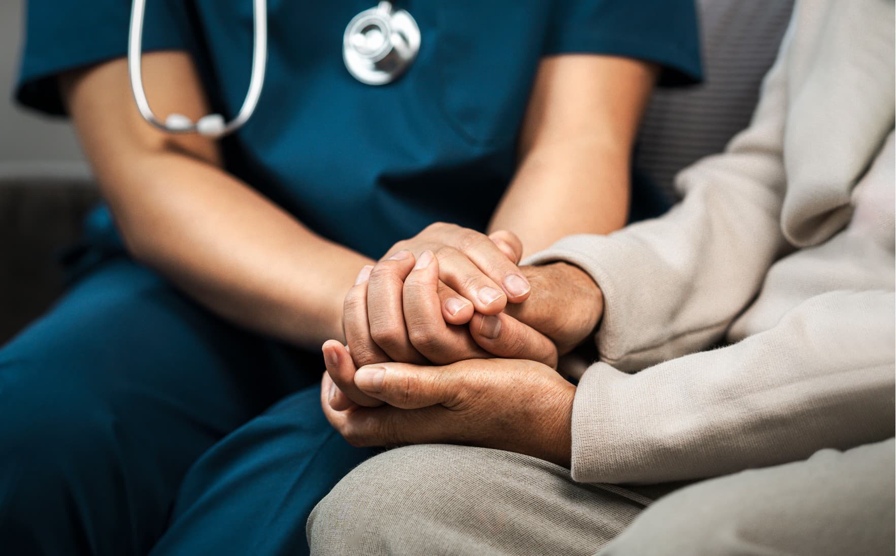 A triage nurse holds hands with a patient, representing improved patient outcomes.