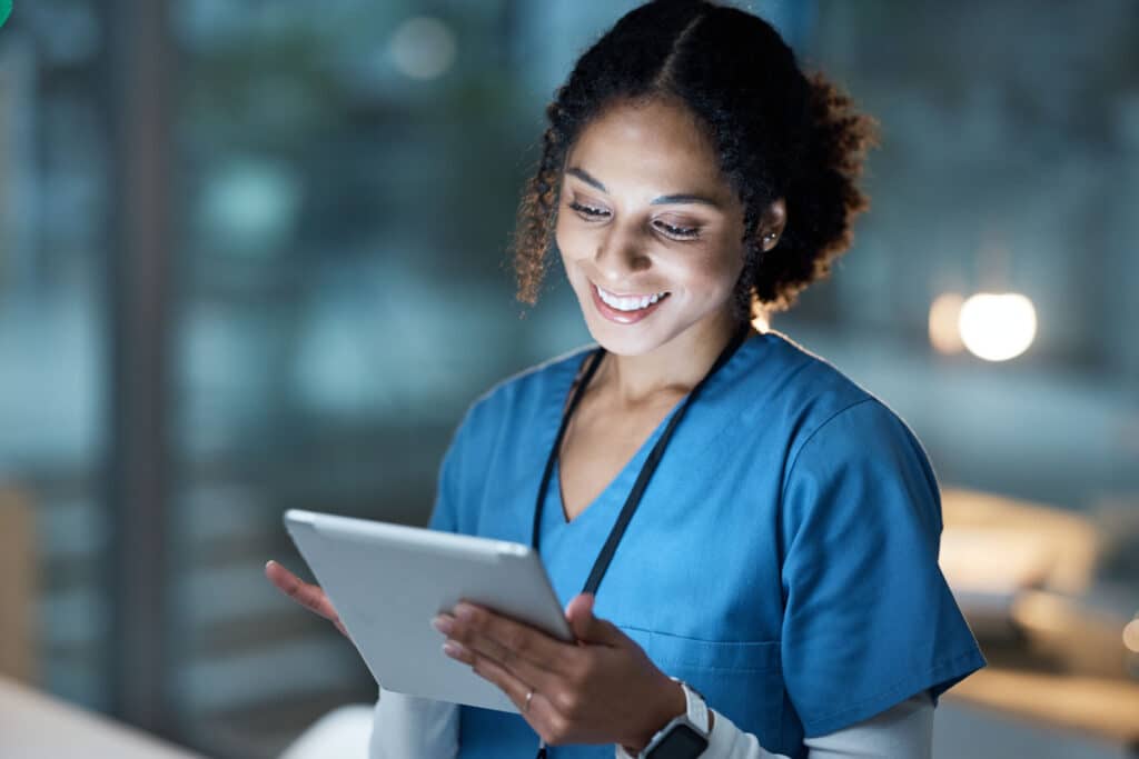 An evening shift nurse reviews patient information on her tablet.