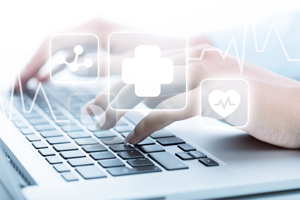 A nurse uses triage software while healthcare icons hover above a laptop keyboard.