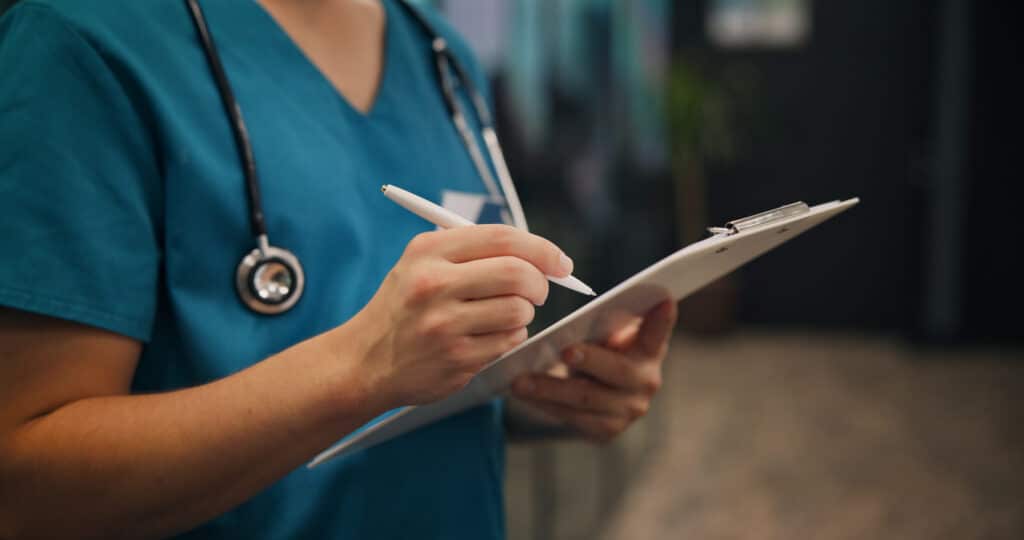 A nurse reviews a checklist on a clipboard.
