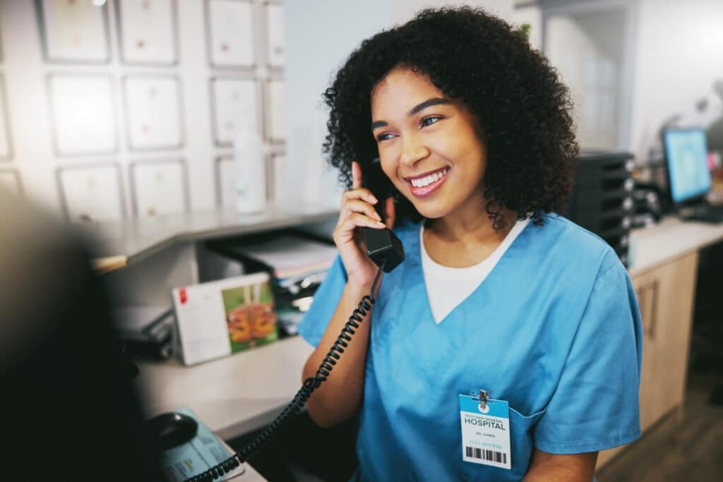 A nurse at a medical practice talks with a patient over the phone.
