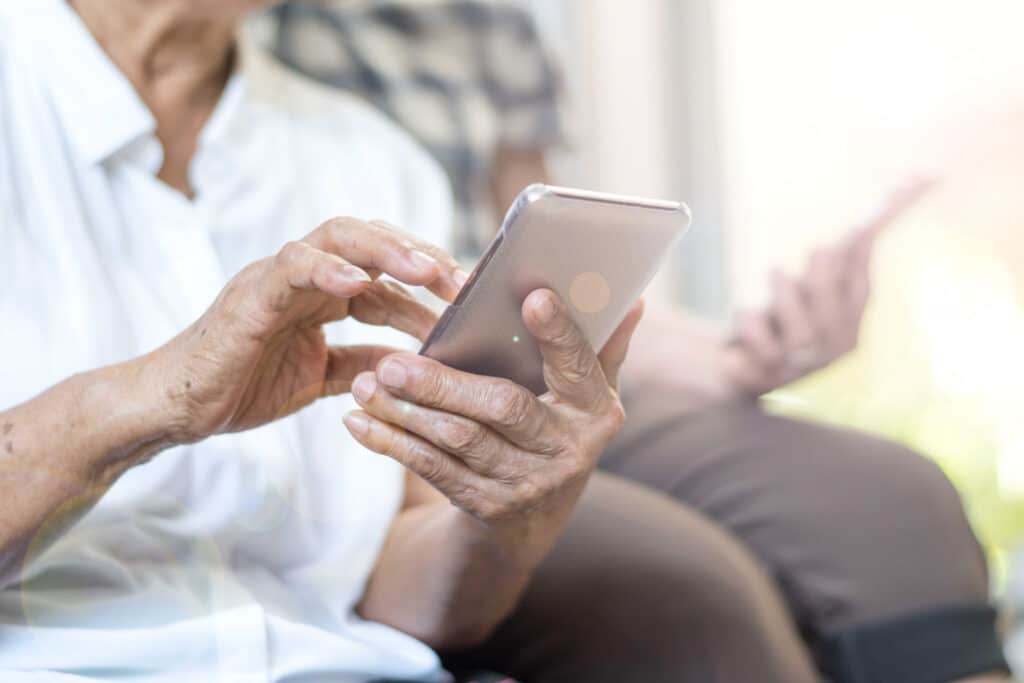 An elderly patient uses a smartphone to report their symptoms using MedMessage Automate.
