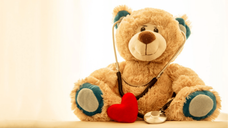 A teddy bear holding a stethoscope and a red heart symbolizes compassionate nurse-led triage and patient safety.