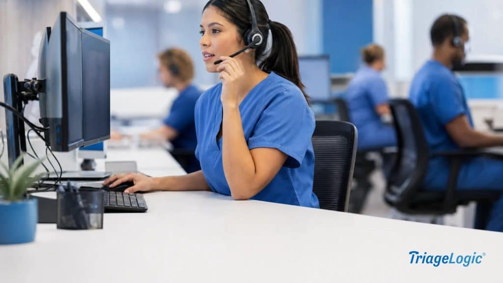 Registered nurse at a triage call center workstation reviewing patient information on dual monitors while speaking via headset.