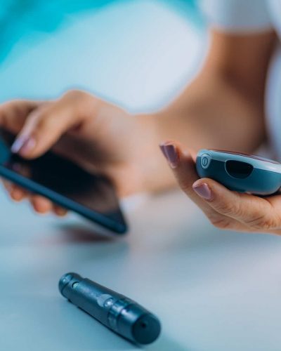 Remote patient monitoring concept: a patient uses a blood sugar testing device in conjunction with their smartphone.