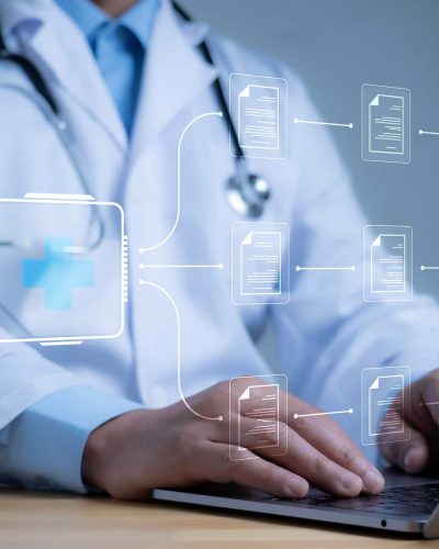 A medical record filing system is superimposed over a doctor working on their laptop.
