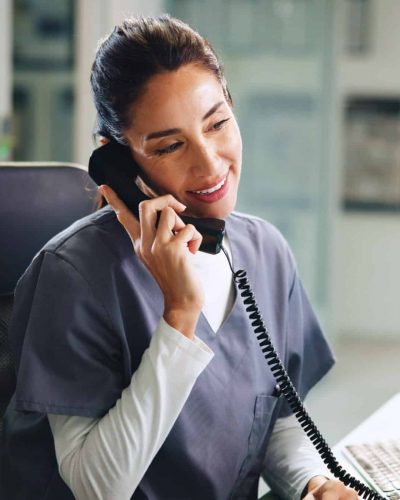After-hours nurse triage services represented by a nurse answering a phone in the evening for a medical practice.