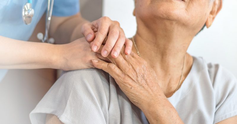A doctor comforts a patient by placing hands on their shoulder.
