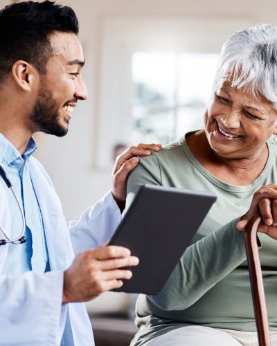 A doctor supports wellness and shares positive test results on his tablet with a geriatric patient.