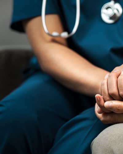 A triage nurse holds hands with a patient, representing improved patient outcomes.