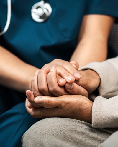 A triage nurse holds hands with a patient, representing improved patient outcomes.