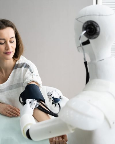 AI in RPM concept: a humanoid robot uses a blood pressure cuff on a woman's arm.