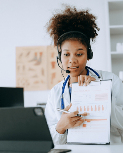 Remote patient monitoring in action: a triage nurse reviews patient health data on a clipboard with a provider over a video call.