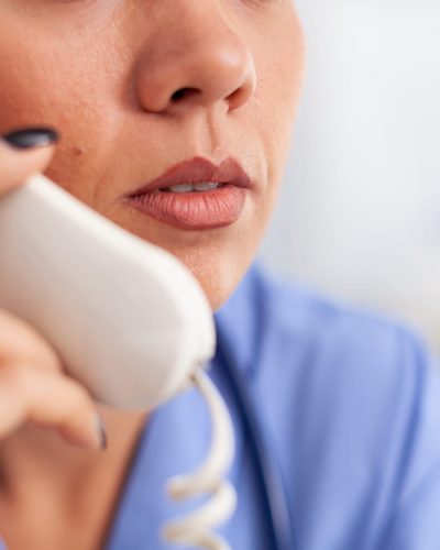 Headshot of a nurse answering a patient call using a landline phone.