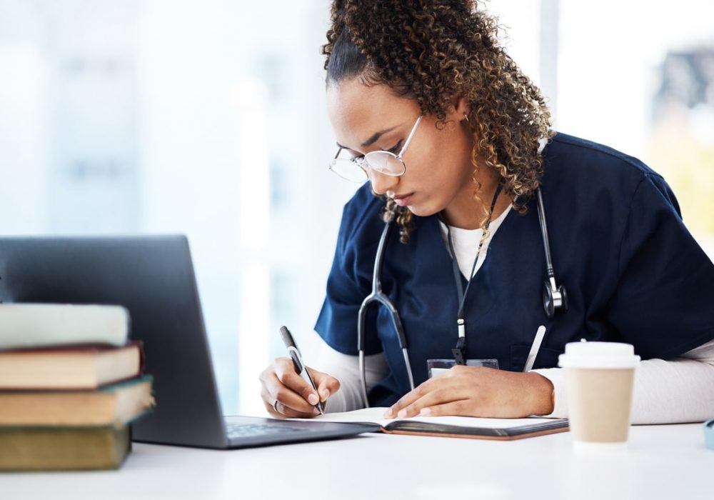 Medical student, thinking or writing books in research education, wellness studying or hospital learning. Laptop, nurse or healthcare woman and notebook, technology or scholarship medicine internship